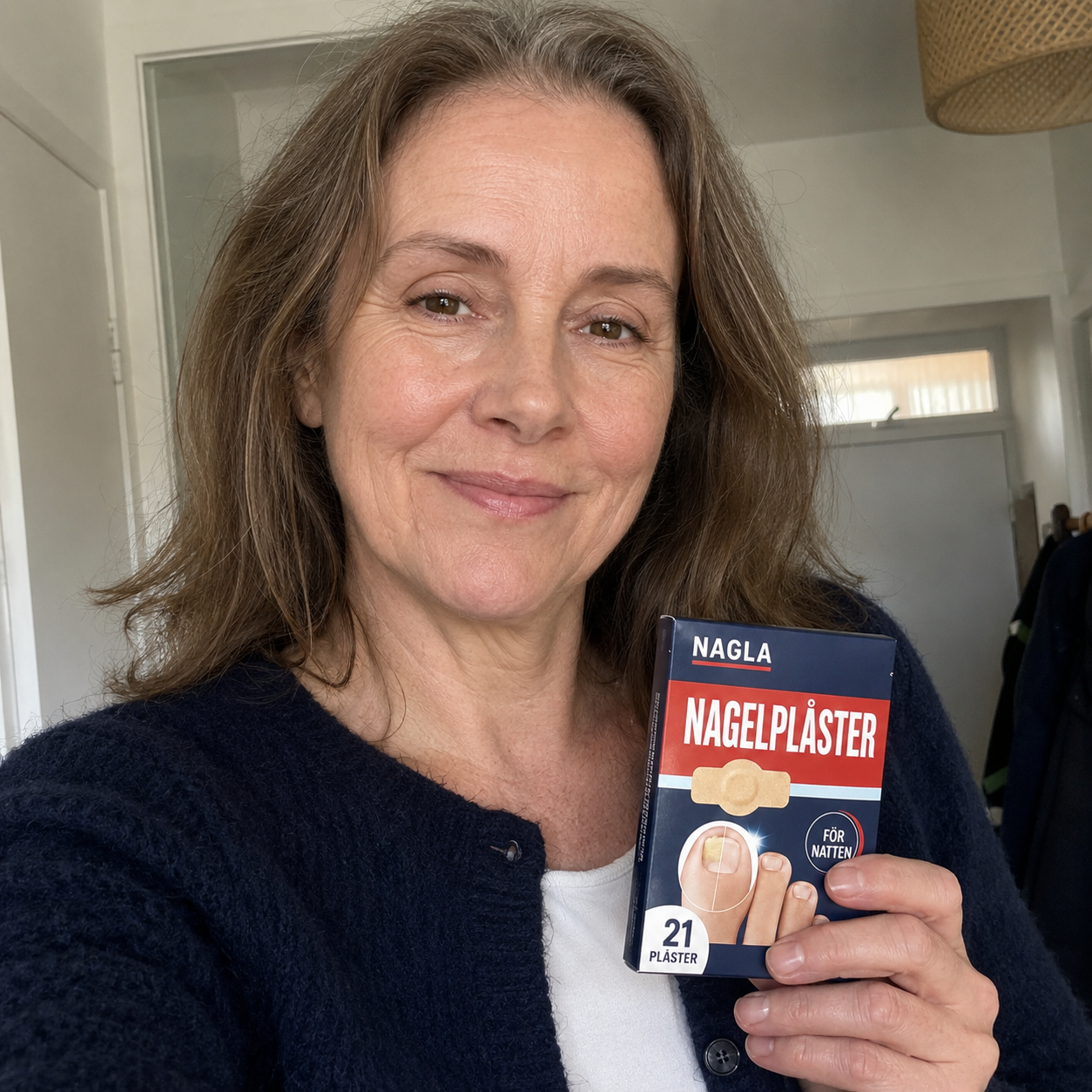 Maria, 58 år håller upp en förpackning NAGLA Nagelplåster